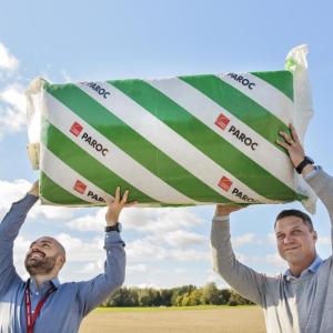 Two people holding up a bat of insulation outside