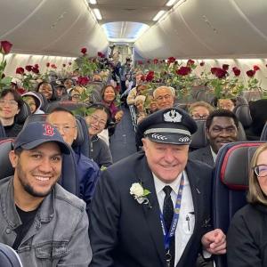 Aeroplane passengers holding roses gifted by Capt. Wayant on mother's day