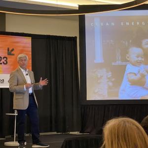 Pedro Pizarro presenting on a small stage, a screen display to his left.