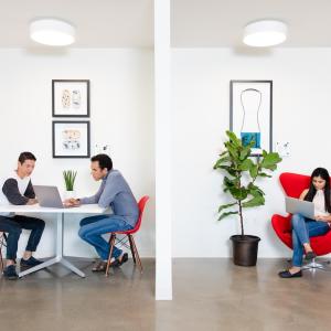 Three people seated and working on laptops.