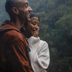 Two people stood close together, laughing in the rain