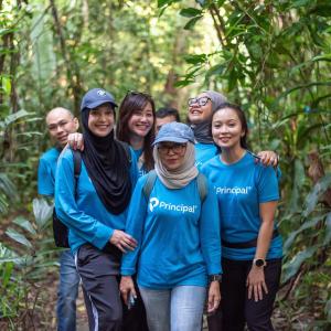 Group of people wearing blue Principal Financial Group shirts in a forest.