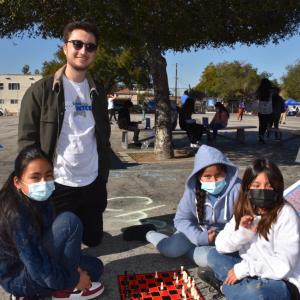 An AEG employee volunteer plays chess with students.