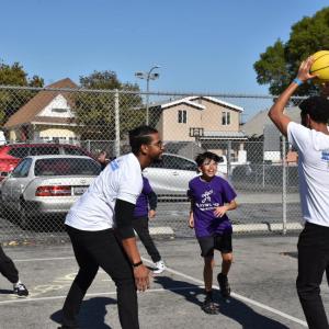 AEG employee volunteers play basketball with students.