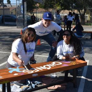 AEG employee volunteers paint a bench.