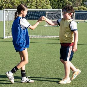 Kids in soccer pinnies fist bumping at Galaxy Park