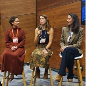 Three women seated on stools talking