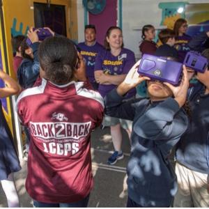 A group of students are interacting with purple VR headsets on the Curiosity Cube.