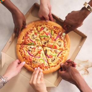 People grabbing a slice of pizza from a box