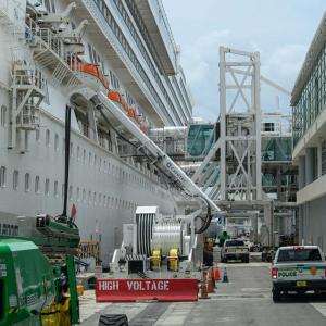 A large boat docked near a narrow roadway and building.