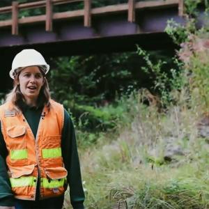 Portia Leigh in hard hat standing near a short bridge.