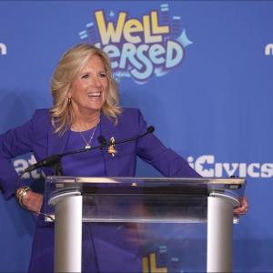 A person stood at a stand at the “Well Versed” premiere, talking into a microphone 