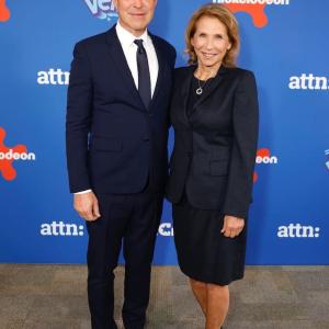 Two people stood together wearing suits in front of a nickelodeon logo backdrop