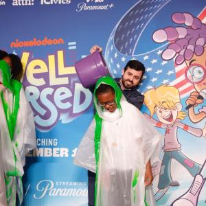 Two people pouring purple buckets of green nickelodeon slime over two other people