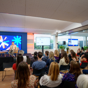 An audience listening to a talk by two people sat on stage