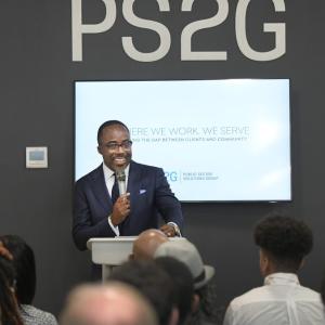 Person stood infront of a crowd, holding a microphone with a screen behind them