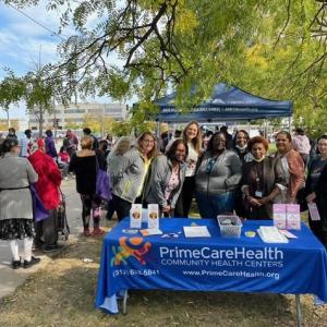 Group standing behind PrimeCare Health table in a park