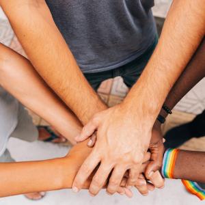 Group of black and white hands joined in the center of a circle.
