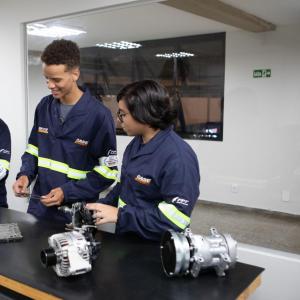 Three people stood at a table looking at mechanical components