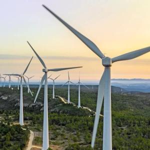 Windmills on top of a hill with the sun setting in the background.