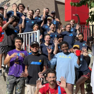 Large group of Publicolor volunteers standing outside of a school