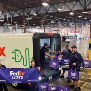 People taking FedEx totes out of a truck