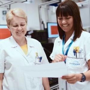 Two female technicians shown reading a report in the HARMAN labs.