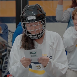 Play like a girl. Young girl shown in a hockey uniform reading a letter.