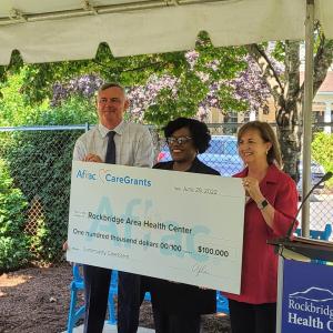Three people holding a check at the presentation event 