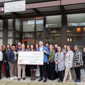 Representatives from KeyBank and REACH shown with a $120,000 grant check.