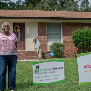 Woman stands in front of her house.