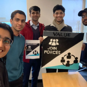 Rahul with friends holding a sign that says: value, join forces.