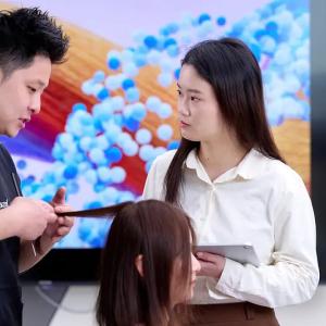 Two people talking as one looks at a seated persons hair.