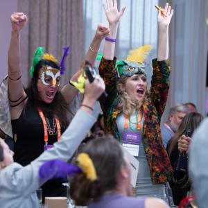 Conference attendees celebrating while wearing Mardi Gras themed hats