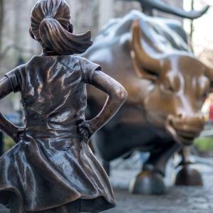 Statues of girl facing a bull