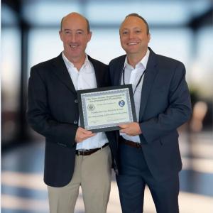 Two people holding up framed award certificate 