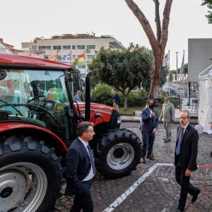 Red tractor parked outside with people walking past 