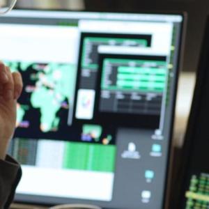 Side angle of someone looking at a computer screens featuring maps