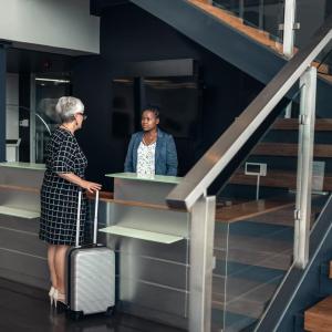 A person checking in at a hotel desk, a staircase to the right.