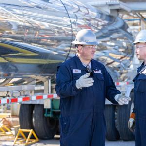 2 workers with hardhats talk outside a truck