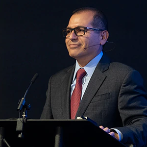 Reymundo at a podium with a microphone, black background