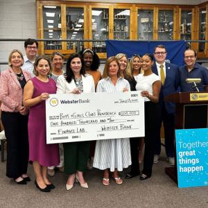 Photo: Marissa Weidner, Chief Corporate Responsibility Officer at Webster Bank (fifth from left) and Nicole Dufresne, CEO, Boys & Girls Clubs of Providence (seventh from left) are joined by members of the Boys & Girls Club team and Webster Bank staff to celebrate the launch of the Webster/Providence Finance Lab at the Boys & Girls Clubs of Providence Fox Point Clubhouse on Tuesday, July 15.
