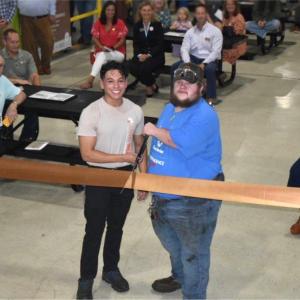 Two people cutting the ribbon in front of people sat on benches
