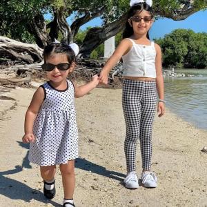 Richa Gandhi's two daughters shown near a pond holding hands.