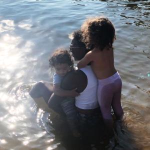 Ricki with her two granddaughters, Belle and Leia sitting in water by a beach