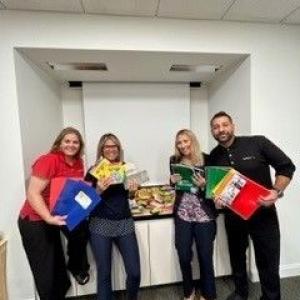 Four people stood together holding Supplies to help children and families 