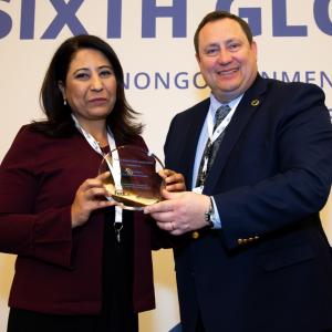 A man and woman posing with an award