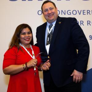 A man and woman posing with an award