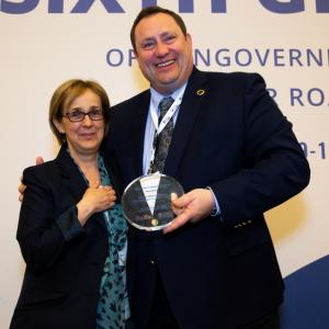 A man and woman posing with an award