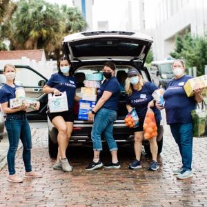 A group of people loading groceries into a car trunk
